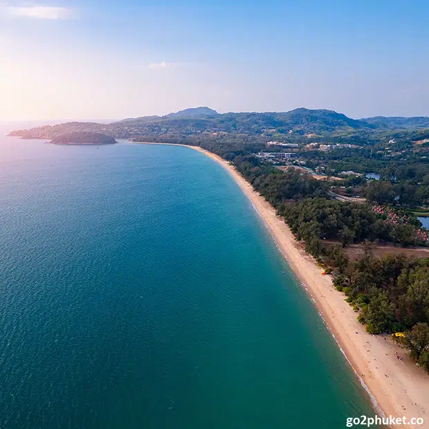 Wide sandy Bang Tao Beach coastline with gentle waves and tropical shoreline on Phuket Island, Thailand