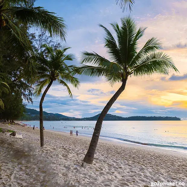 Visitors relaxing and sunbathing on wide sandy Bang Tao Beach beside the Andaman Sea in Phuket, Thailand