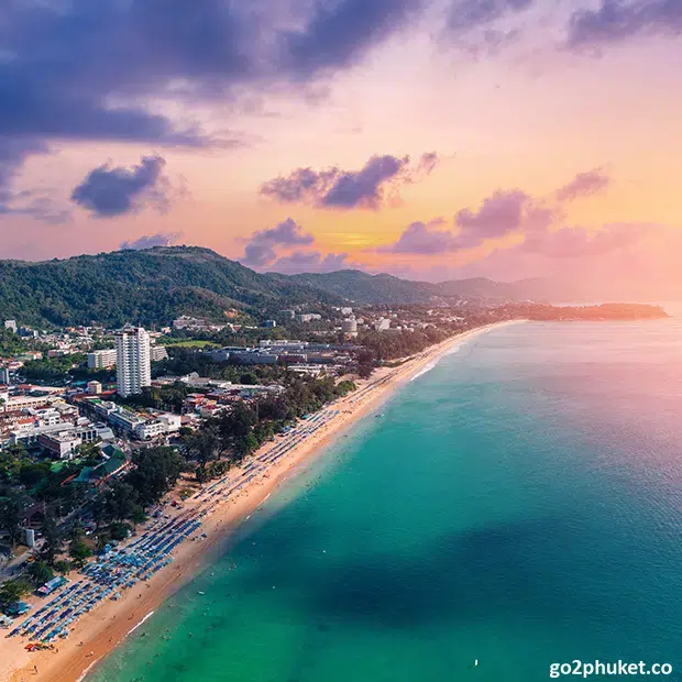 Colorful sunset sky reflecting over the Andaman Sea along the sandy shoreline of Karon Beach in Phuket Thailand.