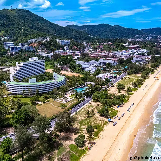 Beachfront hotels and resorts lining the sandy shoreline of Karon Beach on Phuket Island, Thailand.