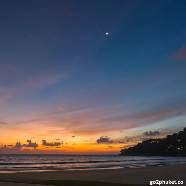 Golden sunset over the Andaman Sea viewed from rocky point overlooking Karon Beach in Phuket Thailand.