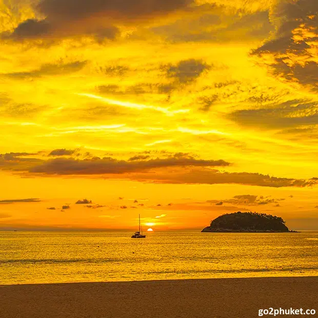 Golden sunset over Andaman Sea with small offshore island visible from Kata Beach, Phuket Thailand