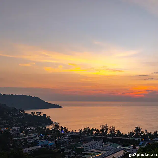 Golden sunset reflecting over calm Andaman Sea waters and sandy shoreline at Kata Beach, Phuket Thailand