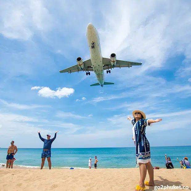 Passenger airplane descending low over Mai Khao Beach shoreline near Phuket International Airport in Phuket, Thailand