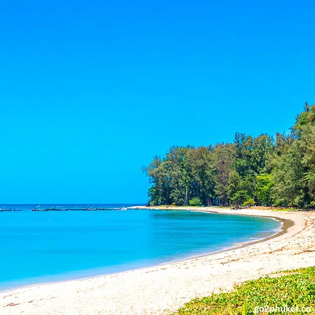 Traditional fishing boats resting on Mai Khao Beach sand beside the Andaman Sea in Phuket, Thailand