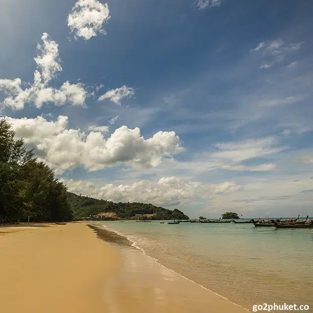 Pristine Nai Yang Beach with fishing boats on calm Andaman Sea and Koh Kala Island in background Phuket Thailand