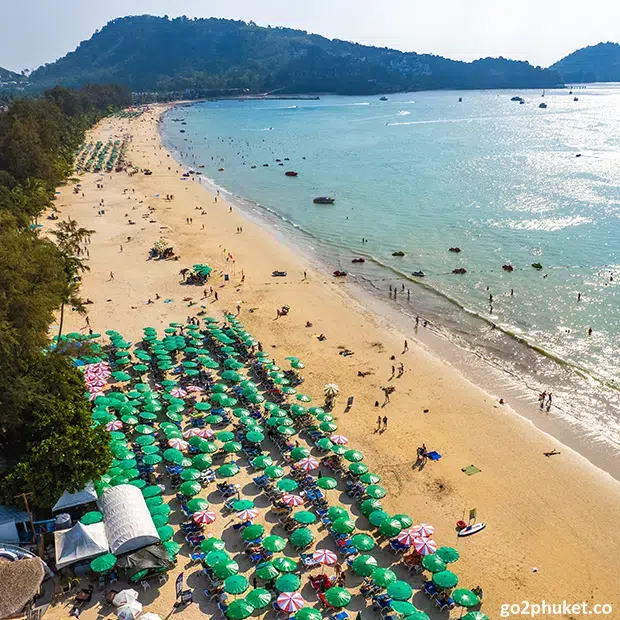 Jet skis lined up on the sandy shore at Patong Beach with Andaman Sea waters in Phuket Thailand.
