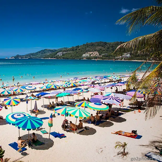 Wide sandy Patong Beach with turquoise Andaman Sea waters and beachfront hotels on Phuket Island, Thailand.