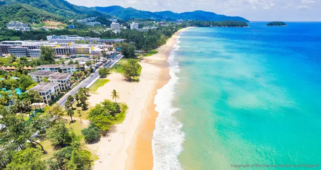 Wide sandy Karon Beach with turquoise Andaman Sea water and rolling waves on Phuket Island, Thailand