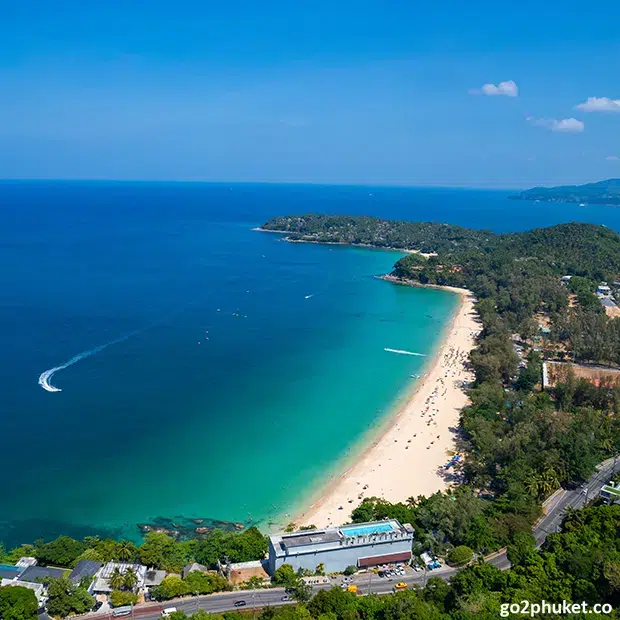 Aerial view of Surin Beach with turquoise Andaman Sea, curved shoreline and tropical greenery in Phuket, Thailand