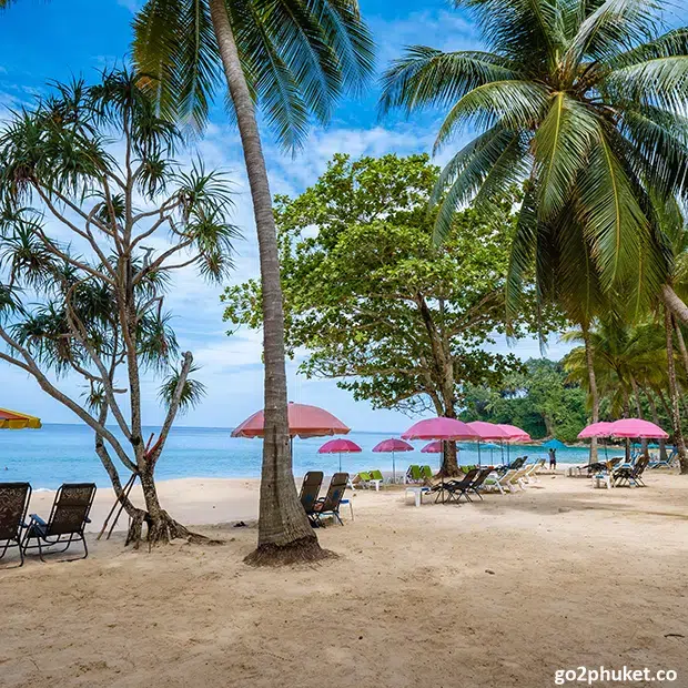 Beach deck chairs and umbrellas arranged on Surin Beach sand overlooking the Andaman Sea in Phuket, Thailand