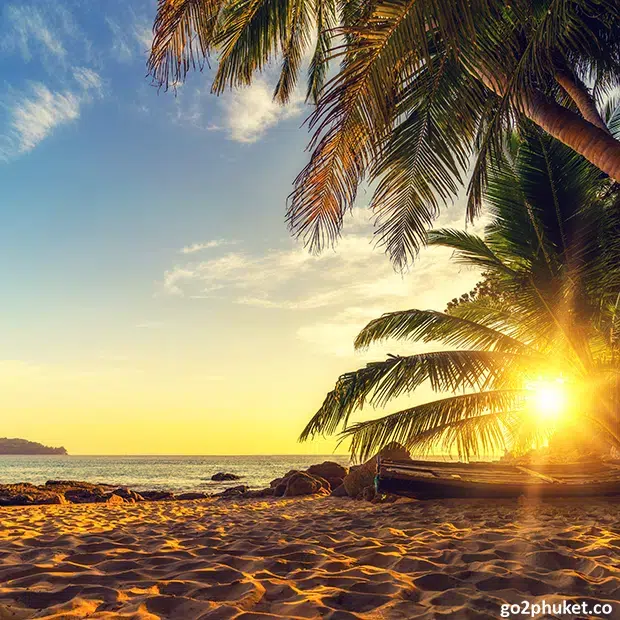 Golden sunset reflecting over calm Andaman Sea waters along Surin Beach shoreline in Phuket, Thailand