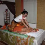 Spa therapist applying hand pressure during traditional Thai body massage treatment at a wellness spa in Thailand