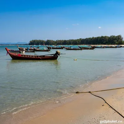 Colorful traditional fishing boats resting on the sandy shore at Nai Yang Beach in Phuket Thailand